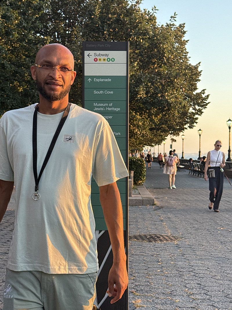 Square Bidness Liberty set walking past Battery Park City signage