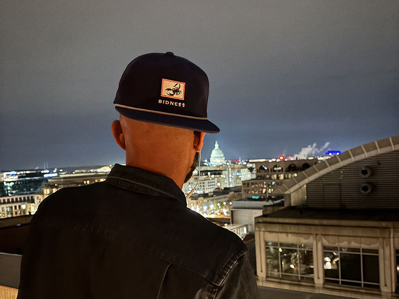 Square Bidness Winter Games waterproof golf hat overlooking the D.C. skyline.